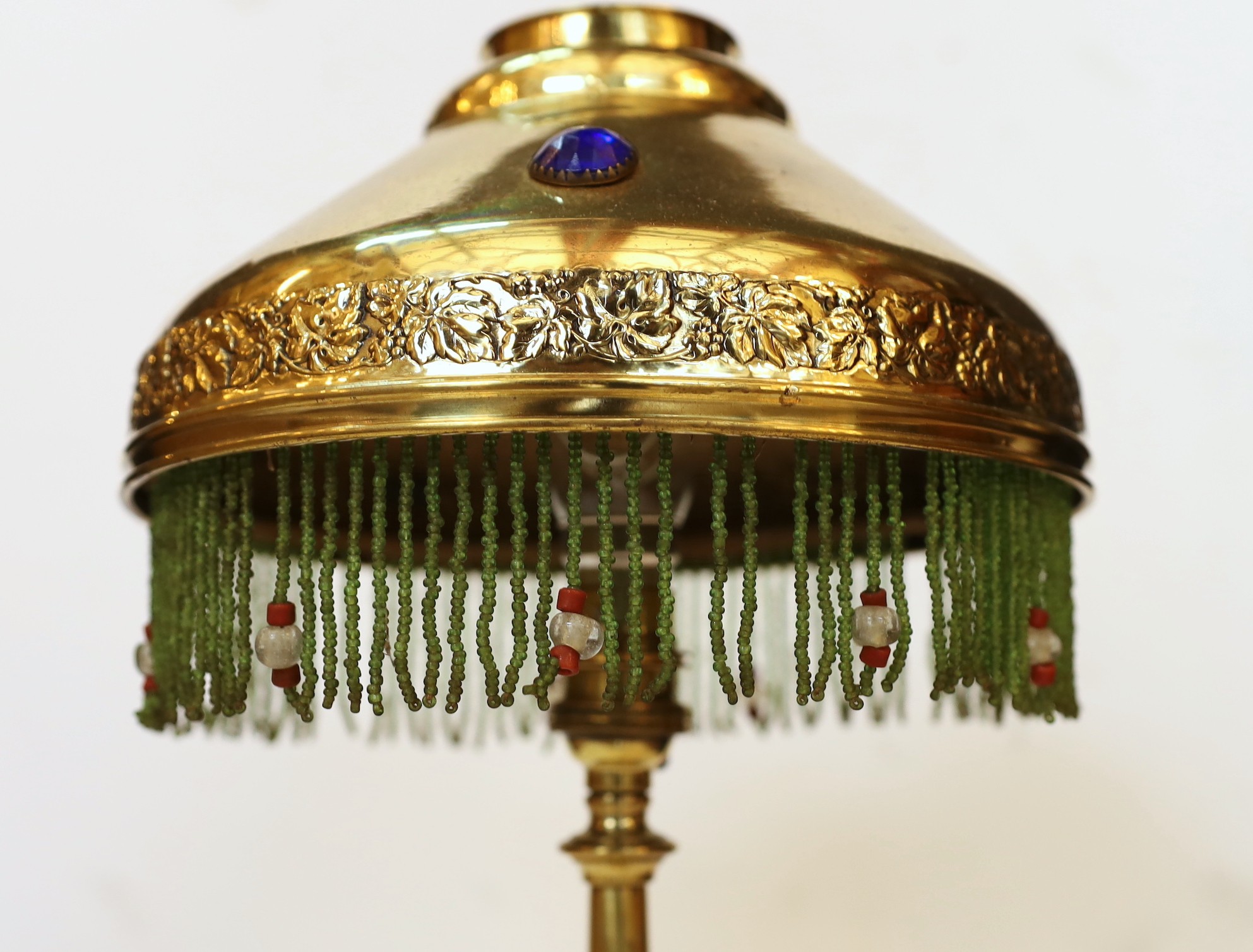 An early 20th century English brass table lamp, the jewelled shade with glass bead fringe, height 45cm